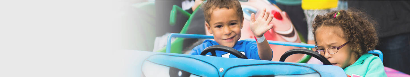 A young boy and girl playing in a big blue toy car.